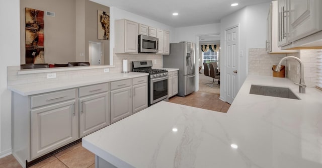 kitchen with light tile patterned flooring, appliances with stainless steel finishes, kitchen peninsula, and sink