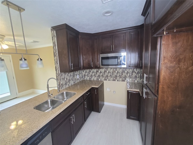 kitchen featuring decorative backsplash, sink, light stone countertops, pendant lighting, and appliances with stainless steel finishes