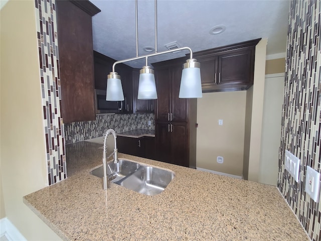 kitchen with decorative backsplash, hanging light fixtures, kitchen peninsula, ornamental molding, and sink