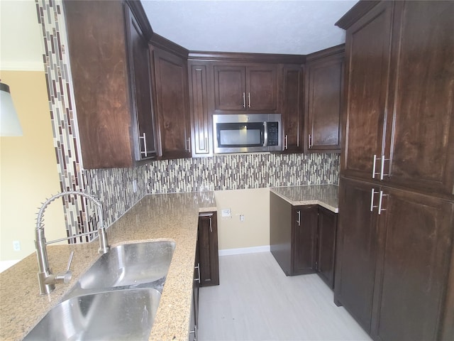 kitchen featuring tasteful backsplash, sink, dark brown cabinets, and light stone counters