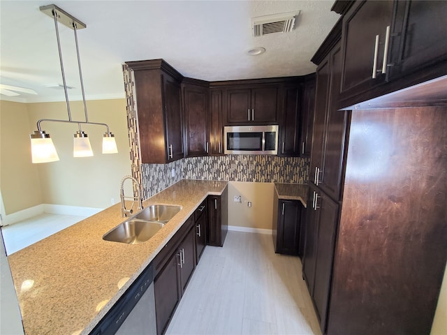 kitchen with sink, pendant lighting, appliances with stainless steel finishes, light stone counters, and tasteful backsplash