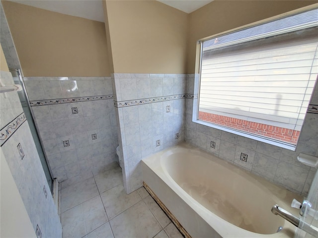 bathroom with a wealth of natural light, tile walls, tile patterned flooring, and a washtub