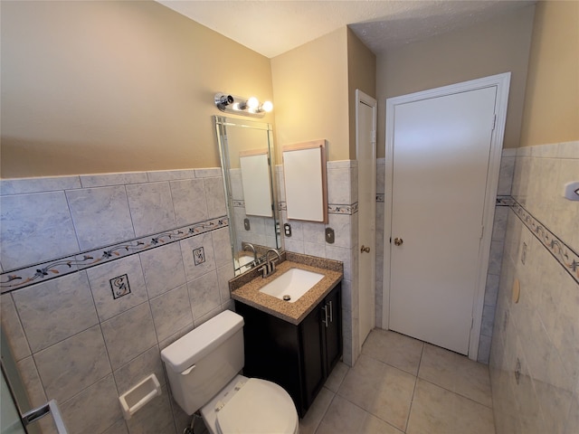 bathroom featuring vanity, toilet, tile walls, and tile patterned flooring