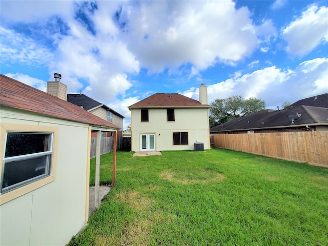 back of property with central AC and a yard