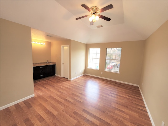 interior space with lofted ceiling, hardwood / wood-style flooring, wet bar, and ceiling fan