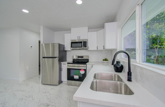 kitchen with a healthy amount of sunlight, appliances with stainless steel finishes, sink, and white cabinets