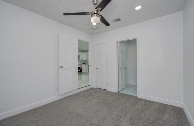 unfurnished bedroom with light carpet, a textured ceiling, and ceiling fan