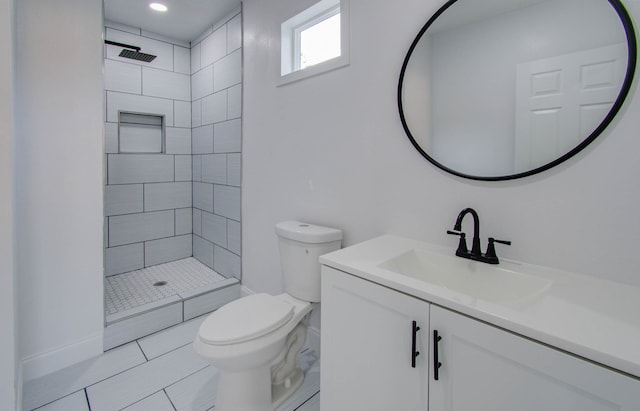 bathroom with vanity, tiled shower, toilet, and tile patterned floors