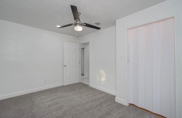 unfurnished bedroom with ceiling fan, light carpet, and a textured ceiling