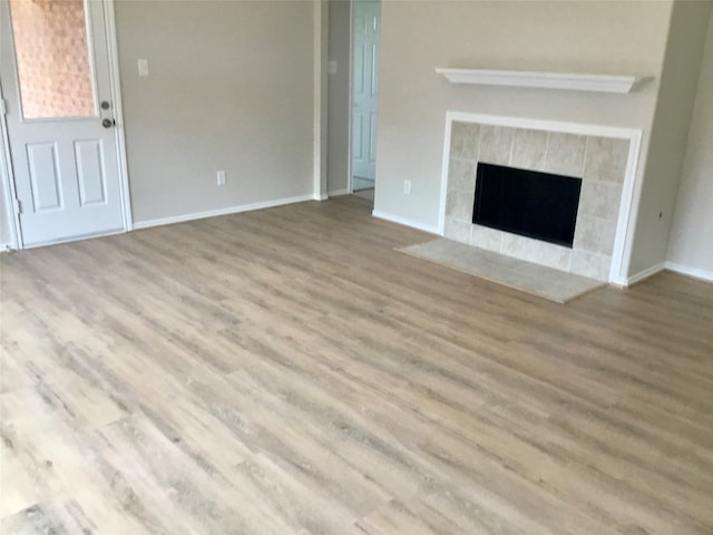 unfurnished living room featuring a tiled fireplace and hardwood / wood-style floors