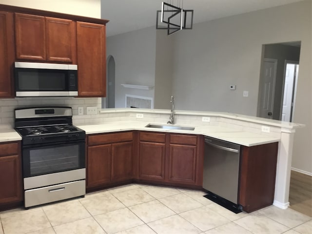 kitchen with kitchen peninsula, decorative backsplash, sink, a notable chandelier, and stainless steel appliances