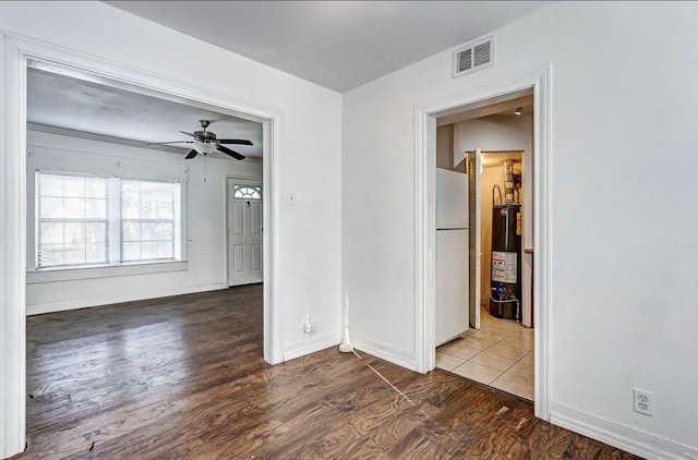 unfurnished room with ceiling fan, gas water heater, and dark wood-type flooring