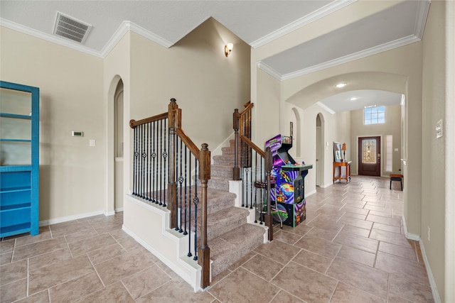 foyer featuring crown molding and a towering ceiling