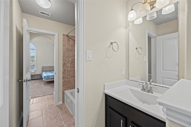 bathroom featuring vanity, tiled shower / bath, a textured ceiling, and tile patterned floors