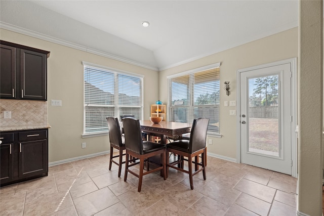 dining room with crown molding, light tile patterned floors, and vaulted ceiling