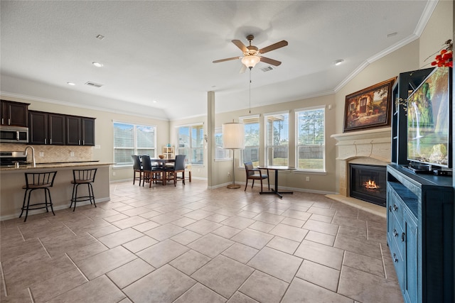 living room featuring ornamental molding, vaulted ceiling, a healthy amount of sunlight, and ceiling fan