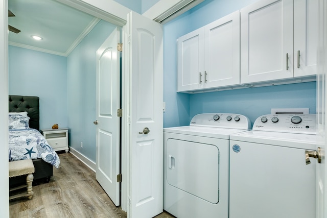 laundry room featuring washer and dryer, ornamental molding, cabinets, and light wood-type flooring