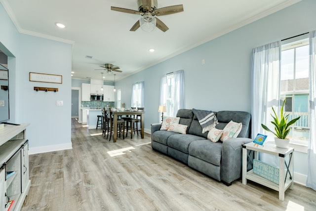 living room with ornamental molding, light wood-type flooring, and ceiling fan