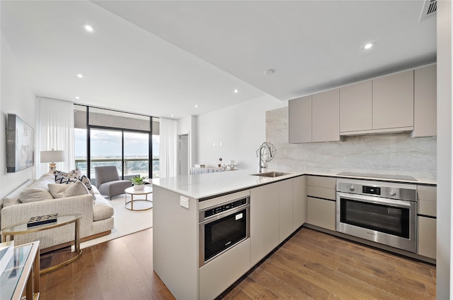 kitchen featuring sink, hardwood / wood-style floors, kitchen peninsula, and oven