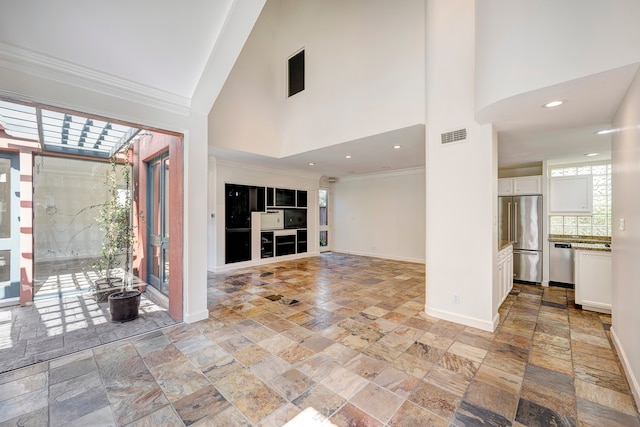 unfurnished living room with ornamental molding and a towering ceiling