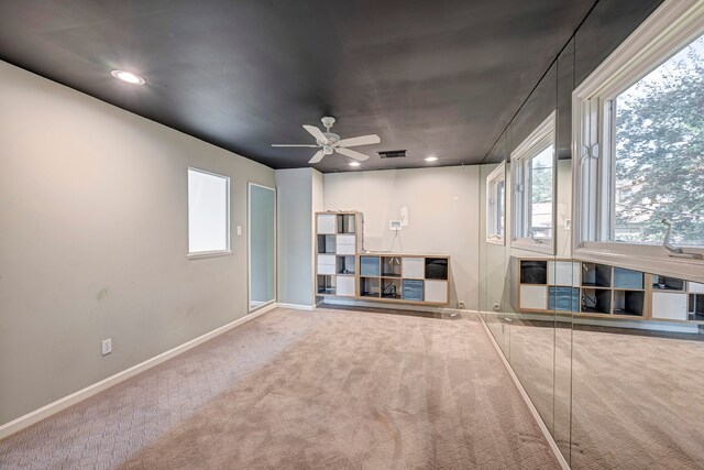 unfurnished living room with ceiling fan and carpet