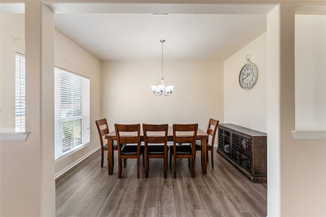 dining room with a chandelier, baseboards, and wood finished floors