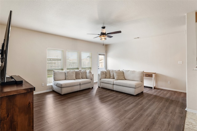 living room featuring ceiling fan, a textured ceiling, and dark hardwood / wood-style flooring