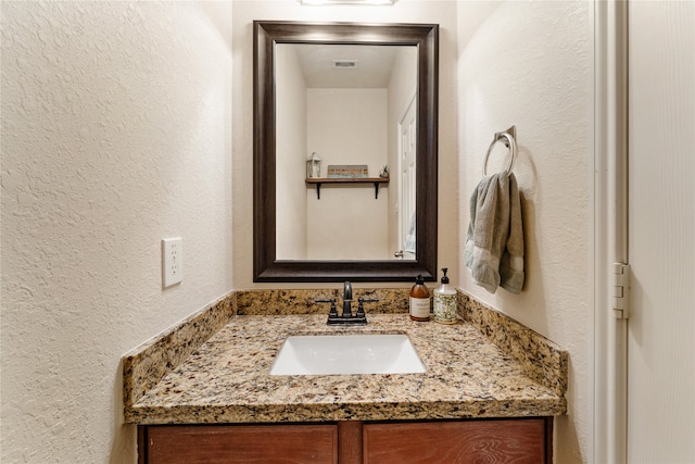 bathroom with visible vents, vanity, and a textured wall