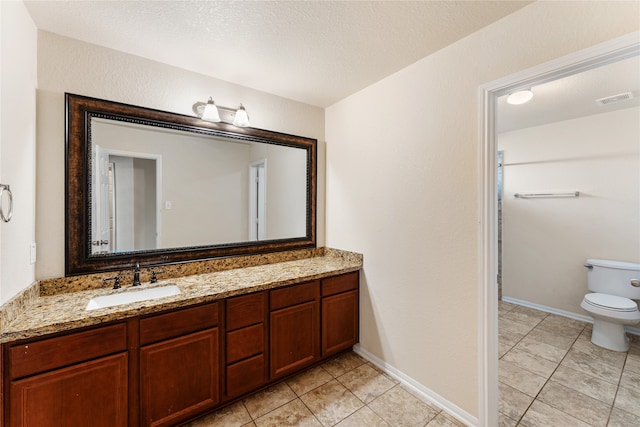 bathroom with vanity, toilet, a textured ceiling, and tile patterned flooring