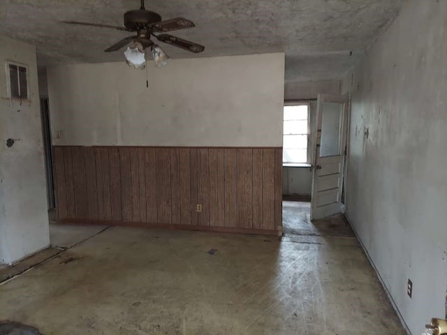 spare room featuring wooden walls and ceiling fan