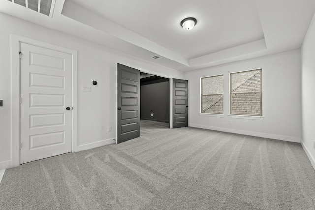 unfurnished bedroom featuring a raised ceiling and carpet floors