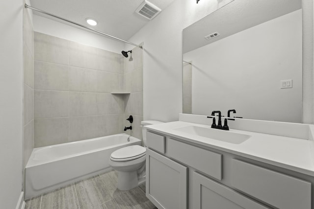 full bathroom featuring vanity, tiled shower / bath combo, and toilet