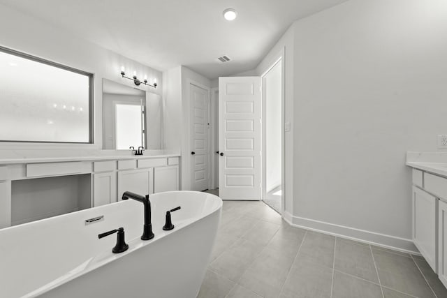 bathroom featuring tile patterned flooring, vanity, and a bath