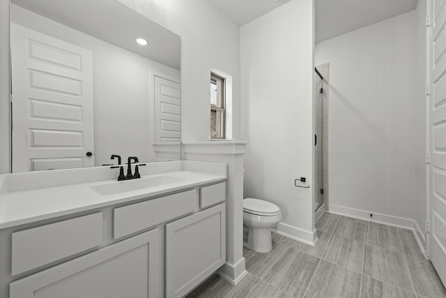 bathroom with vanity, toilet, and a shower with shower door