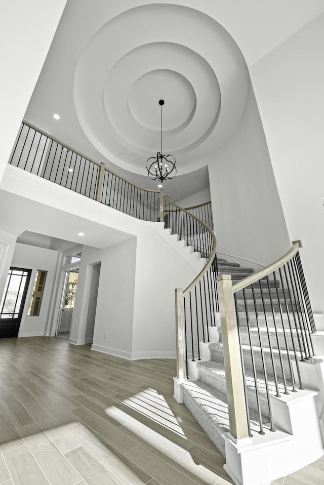 stairs with a chandelier, a high ceiling, and hardwood / wood-style floors