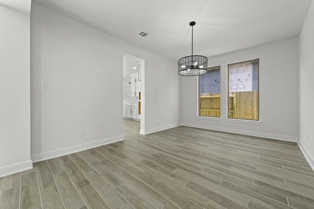 unfurnished dining area featuring light hardwood / wood-style floors and an inviting chandelier