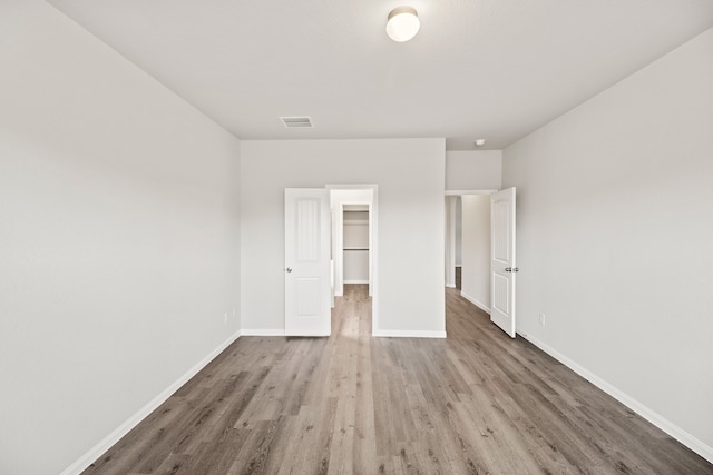 unfurnished bedroom featuring light hardwood / wood-style floors, a walk in closet, and a closet