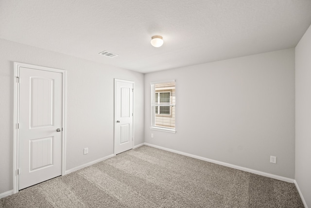 carpeted empty room featuring a textured ceiling