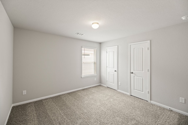 carpeted empty room featuring a textured ceiling