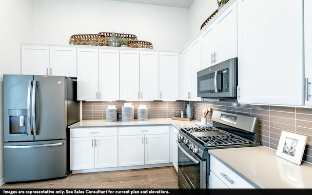 kitchen with white cabinets, appliances with stainless steel finishes, tasteful backsplash, light countertops, and light wood-type flooring