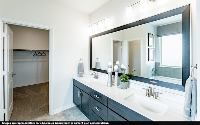 full bath featuring double vanity, a sink, tile patterned floors, and a spacious closet
