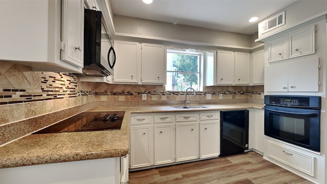 kitchen with black appliances, sink, light wood-type flooring, white cabinetry, and decorative backsplash