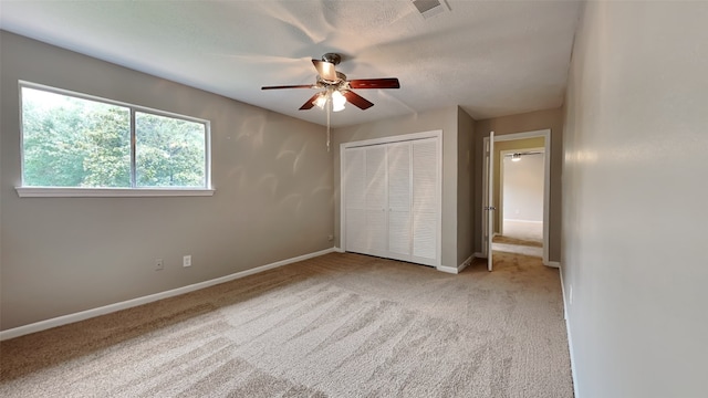 unfurnished bedroom with a closet, light colored carpet, and ceiling fan