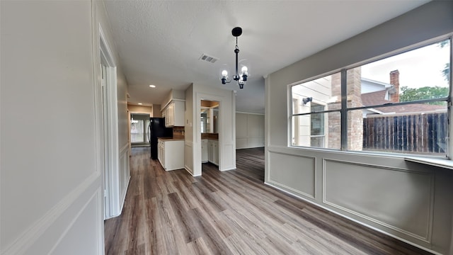 unfurnished dining area featuring a chandelier and light wood-type flooring