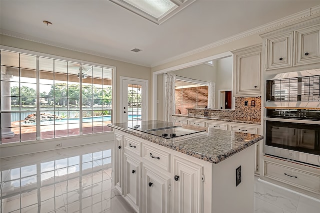 kitchen with stainless steel microwave, tasteful backsplash, stone countertops, black electric stovetop, and a kitchen island