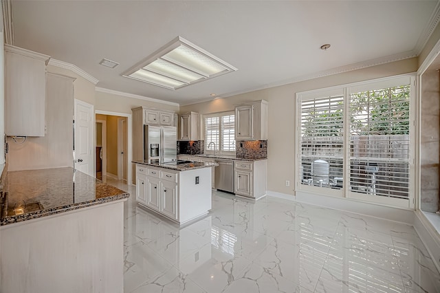 kitchen featuring appliances with stainless steel finishes, dark stone counters, ornamental molding, sink, and white cabinetry