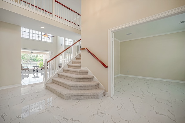 staircase featuring ceiling fan and a high ceiling