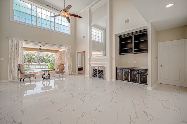 unfurnished living room with a fireplace, a high ceiling, and ceiling fan