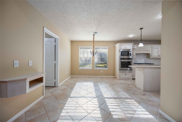 kitchen featuring appliances with stainless steel finishes, a notable chandelier, white cabinets, decorative light fixtures, and backsplash