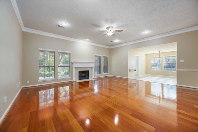 unfurnished living room with ceiling fan with notable chandelier, a textured ceiling, and crown molding